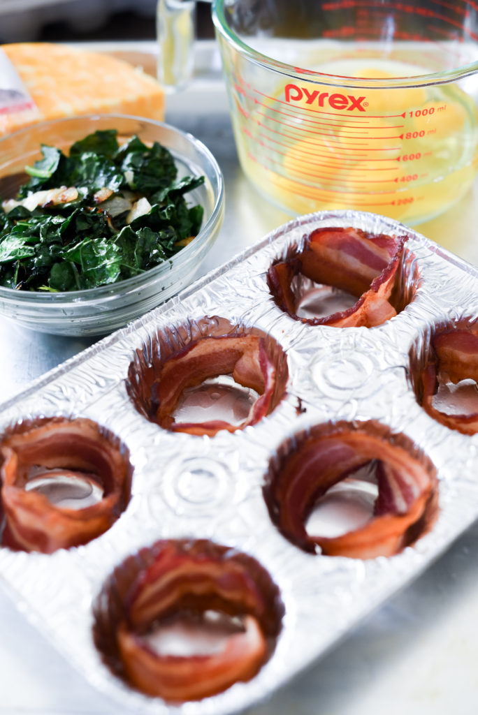 Grilled Eggs Cup perfect for a summer meal prep: Light fluffy eggs, stuffed w/ greens, caramelized onions, & cheese wrapped in a piece of bacon. 