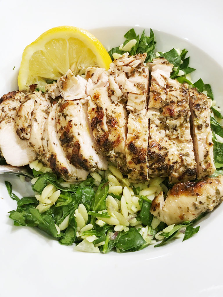 Greek marinated chicken served over a warm orzo and spinach salad with salty feta and red onion drizzled with a sweet/ tart red wine vinaigrette. 